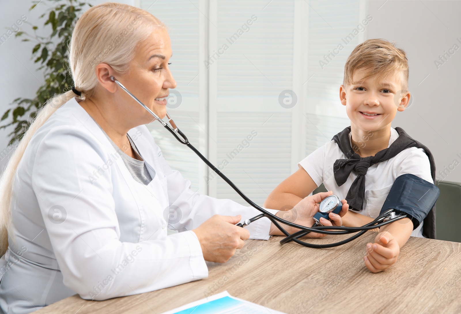 Photo of Little boy visiting doctor in hospital. Measuring blood pressure and checking pulse