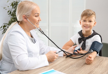 Little boy visiting doctor in hospital. Measuring blood pressure and checking pulse