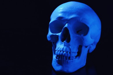 Photo of Blue human skull on black background, space for text