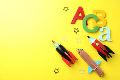 Bright toy rockets and school supplies on yellow background, flat lay. Space for text