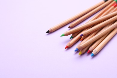 Photo of Many colorful pastel pencils on violet background, space for text. Drawing supplies