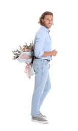 Photo of Young handsome man hiding beautiful flower bouquet behind his back on white background
