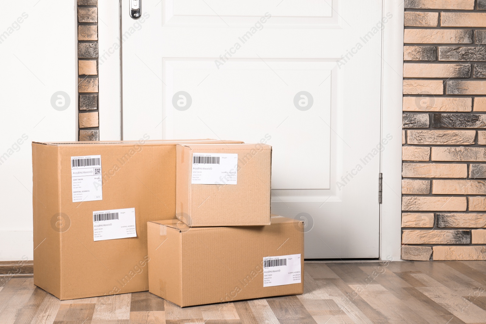 Photo of Cardboard parcel boxes on floor near apartment entrance. Mockup for design