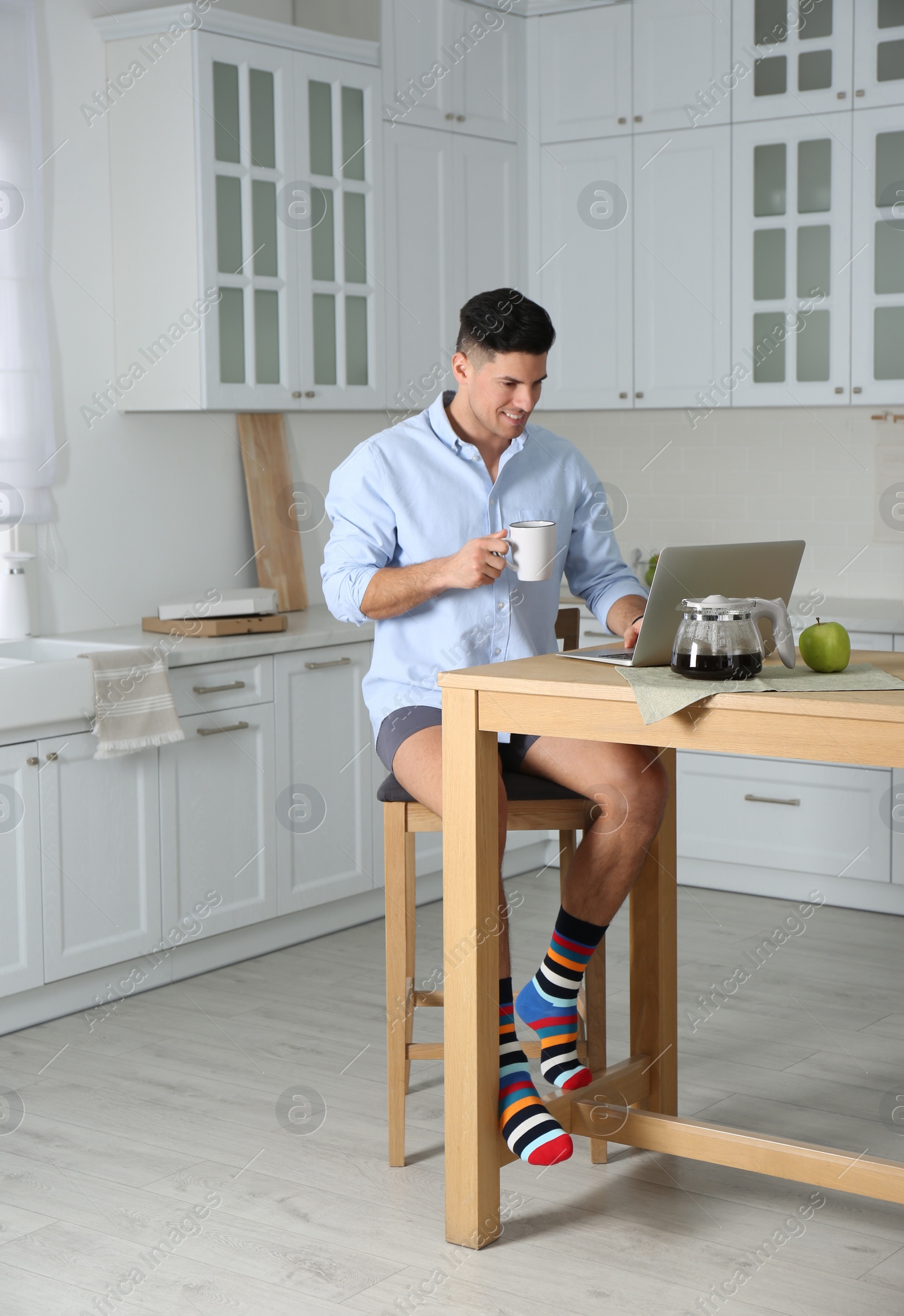 Photo of Businessman in shirt and underwear working on laptop at home