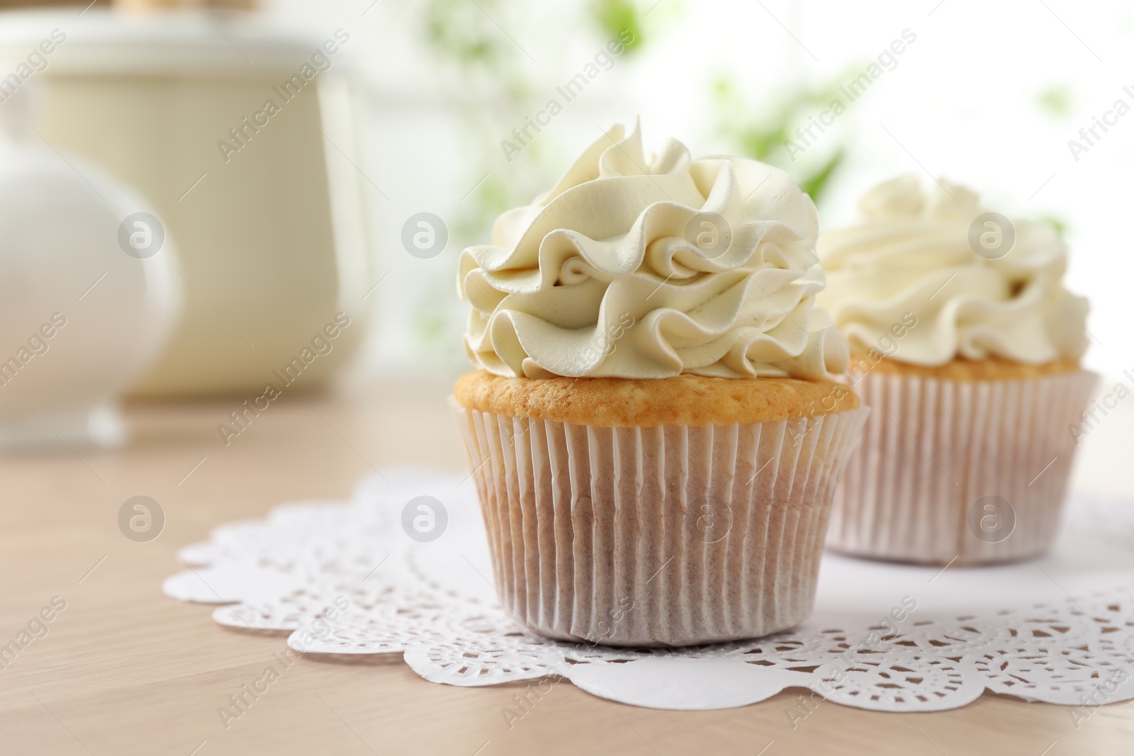 Photo of Tasty cupcakes with vanilla cream on light wooden table, closeup