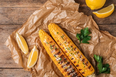 Photo of Flat lay composition of grilled corn cobs on wooden table