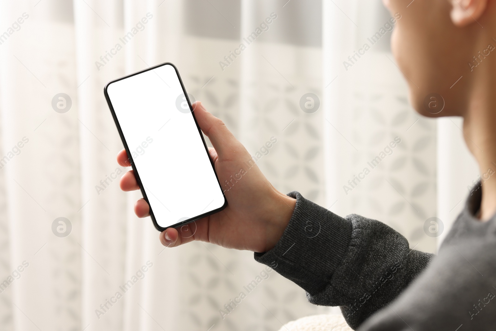 Photo of Man using smartphone with blank screen indoors, closeup. Mockup for design