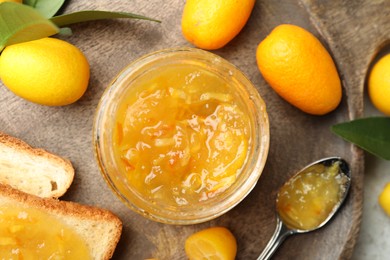 Delicious kumquat jam, tasty toasts and fresh fruits on wooden board, flat lay