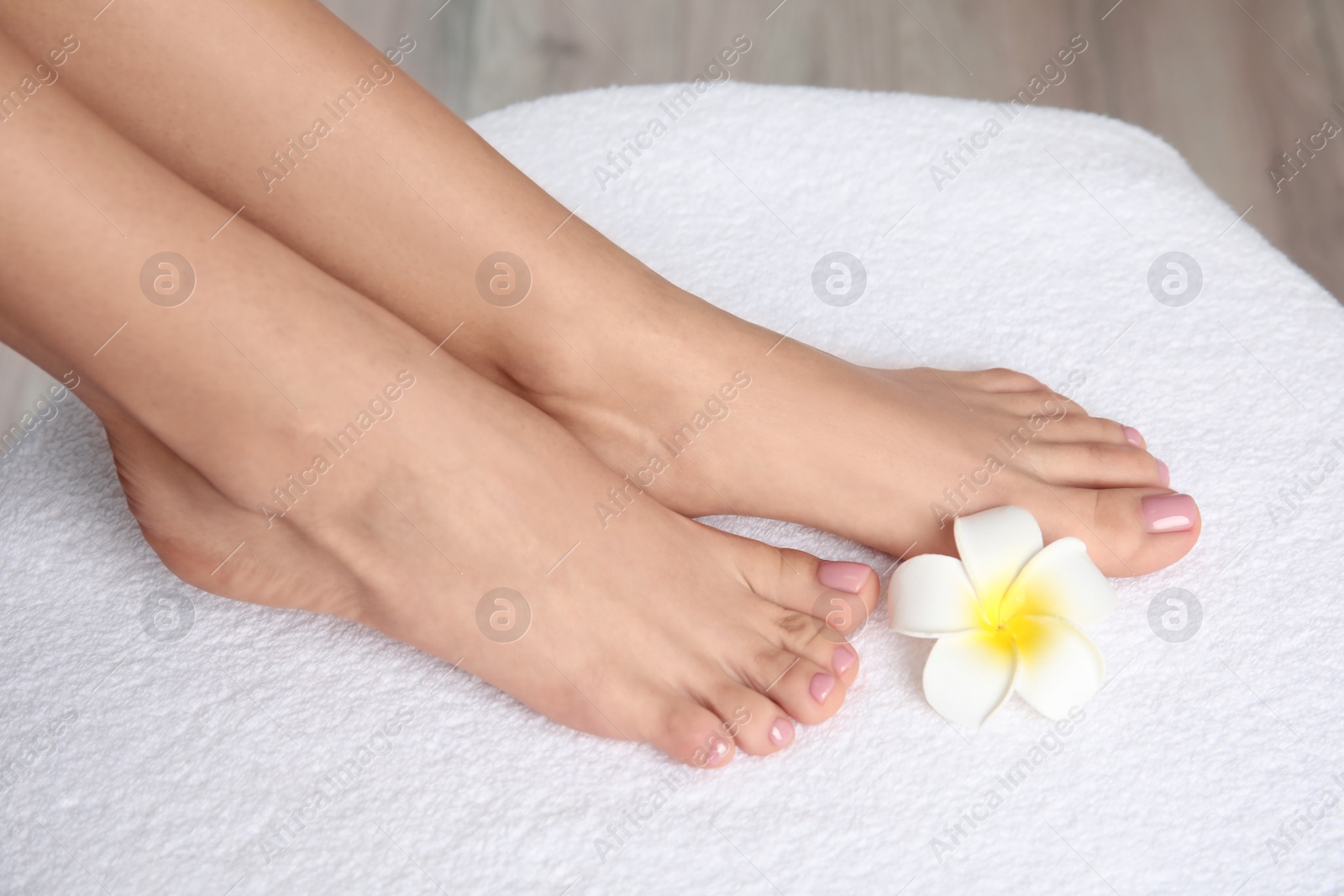 Photo of Woman with smooth feet on white towel, closeup. Spa treatment