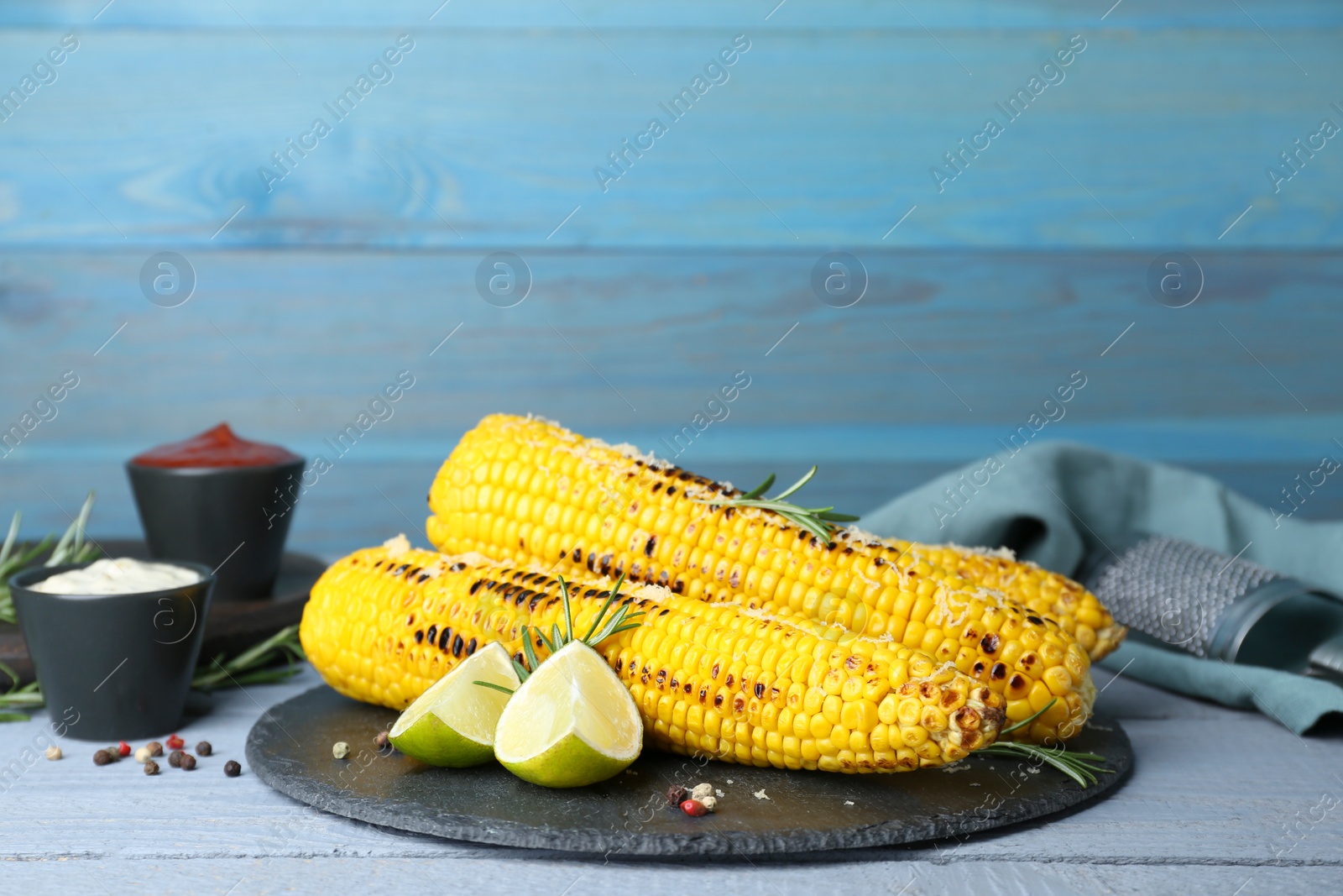 Photo of Tasty fried corn, spices and ingredients on light blue wooden table