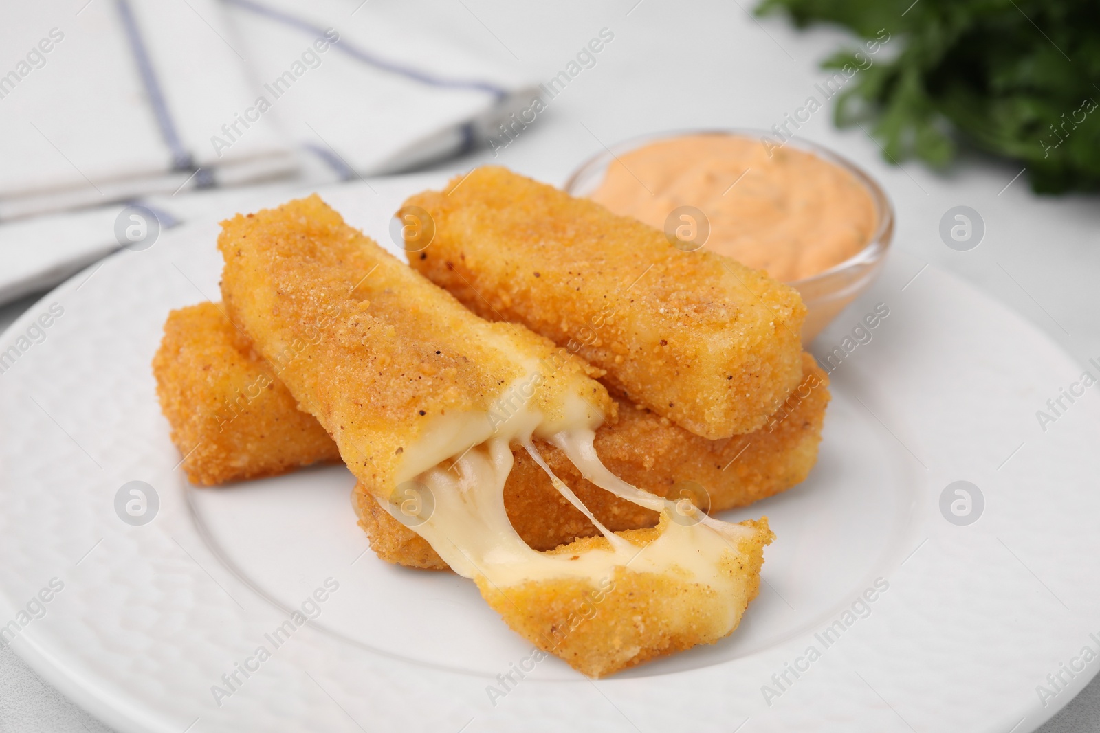 Photo of Plate with tasty fried mozzarella sticks and sauce on light table, closeup