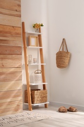 Stylish room interior with wooden ladder near white wall