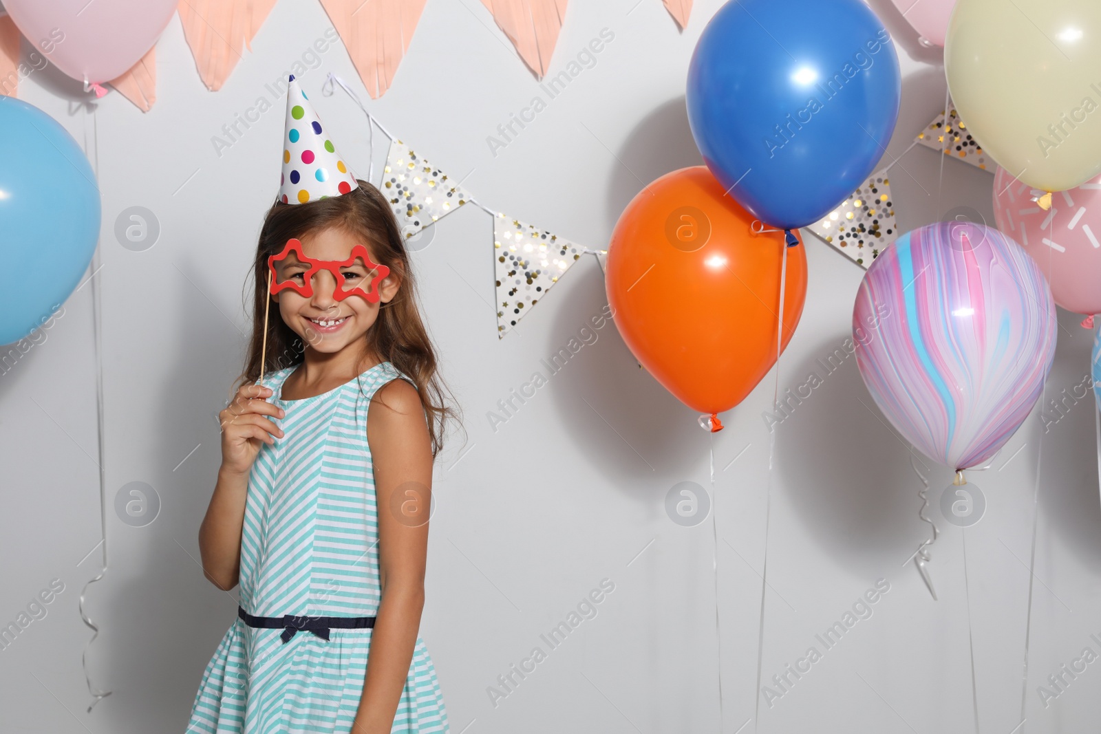 Photo of Happy girl near bright balloons at birthday party indoors