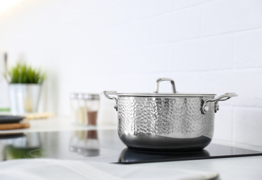 Photo of New shiny saucepan on stove in kitchen