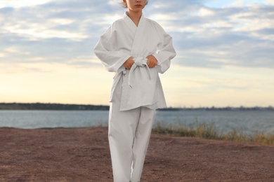 Photo of Cute little girl in kimono near river. Karate practicing