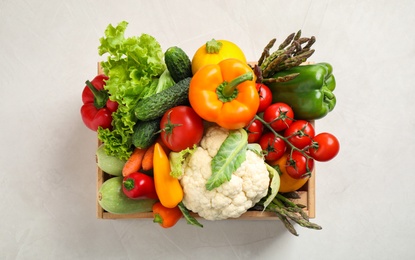 Wooden crate with fresh vegetables on white background, top view