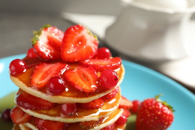 Photo of Tasty pancakes with berries and honey on plate, closeup