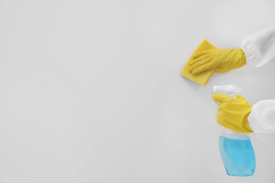 Photo of Woman in protective suit cleaning mold with sprayer and rag on wall, closeup. Space for text