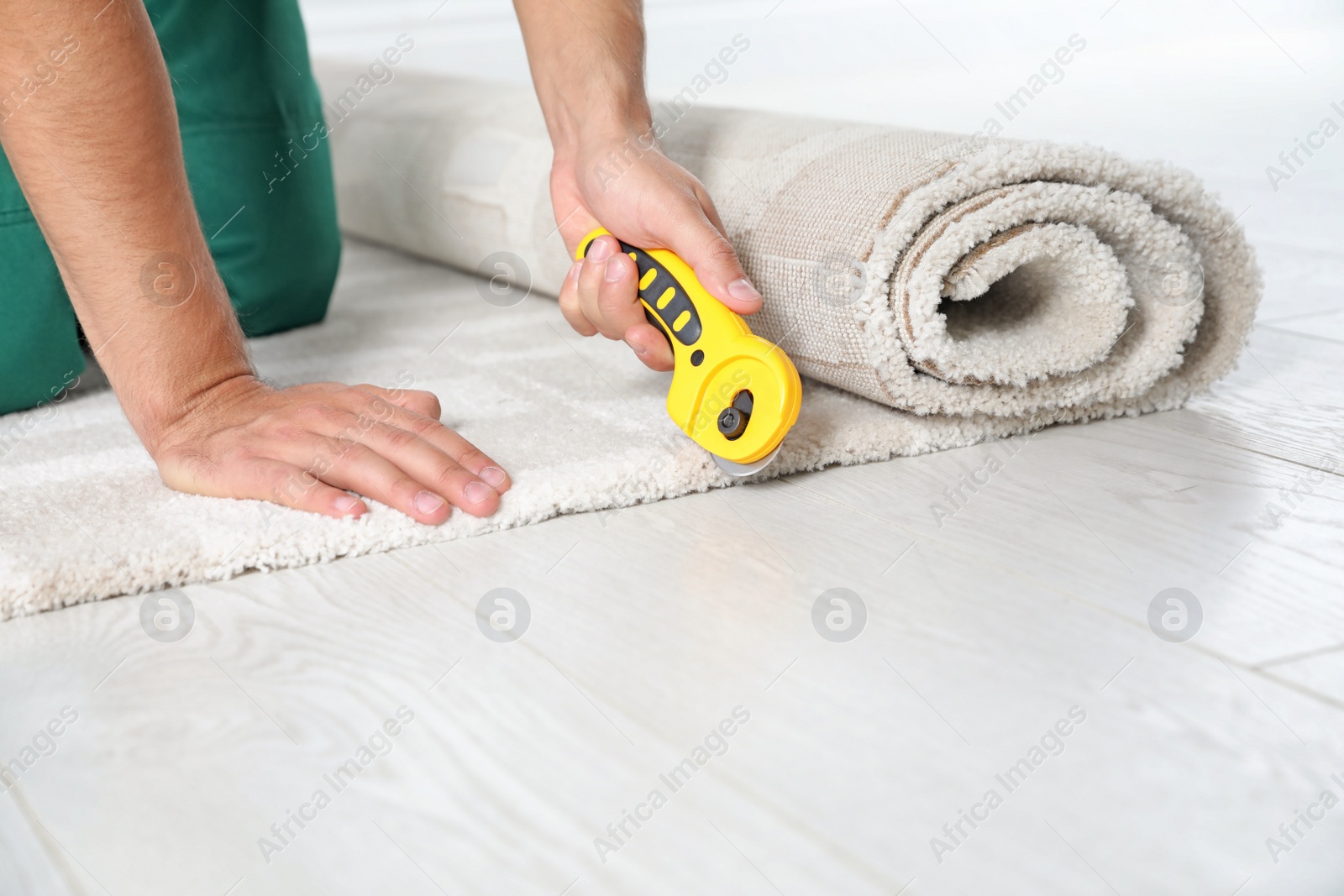 Photo of Man cutting new carpet flooring indoors, closeup. Space for text