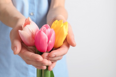 Photo of Girl holding beautiful spring tulips on light background, closeup. International Women's Day