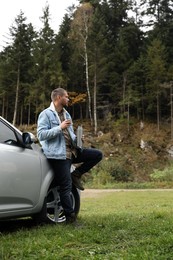 Man with metallic thermos and cup lid near car outdoors