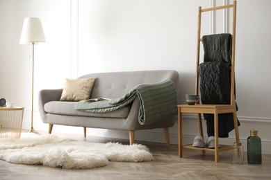 Photo of Knitted plaids on chair near sofa in living room