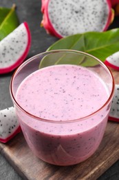 Photo of Delicious pitahaya smoothie and fresh fruits on black table, closeup