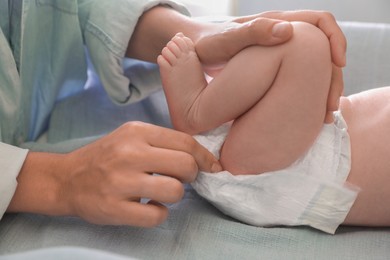 Photo of Mother changing baby's diaper on table, closeup