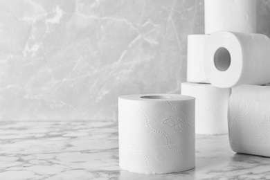 Photo of Rolls of toilet paper on marble table. Space for text