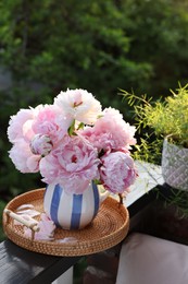 Photo of Beautiful pink peony flowers in vase on balcony railing outdoors