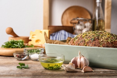 Photo of Tasty homemade garlic bread with cheese and herbs on wooden table in kitchen. Space for text