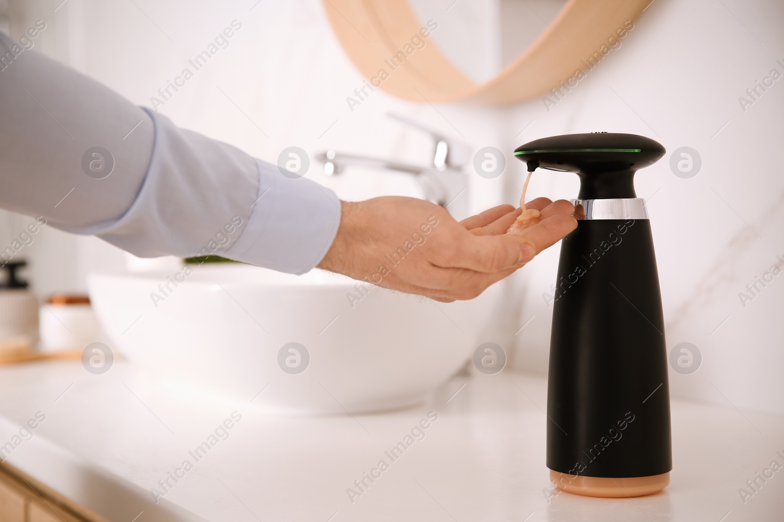 Photo of Man using automatic soap dispenser in bathroom, closeup