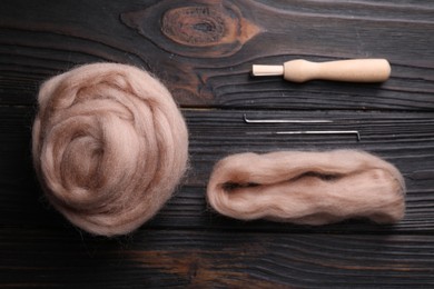 Photo of Beige felting wool and needles on wooden table, flat lay