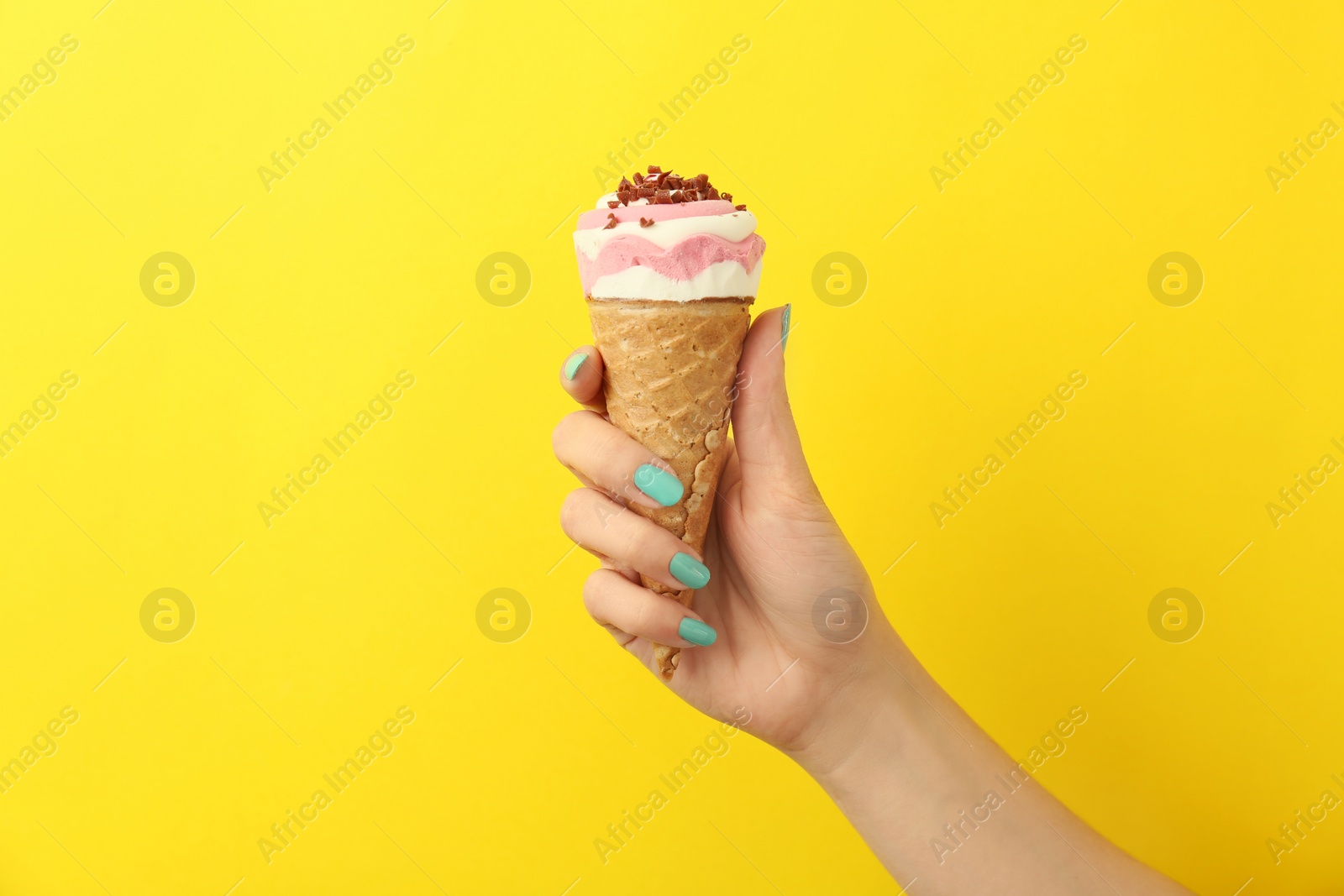 Photo of Woman holding yummy ice cream on color background. Focus on hand