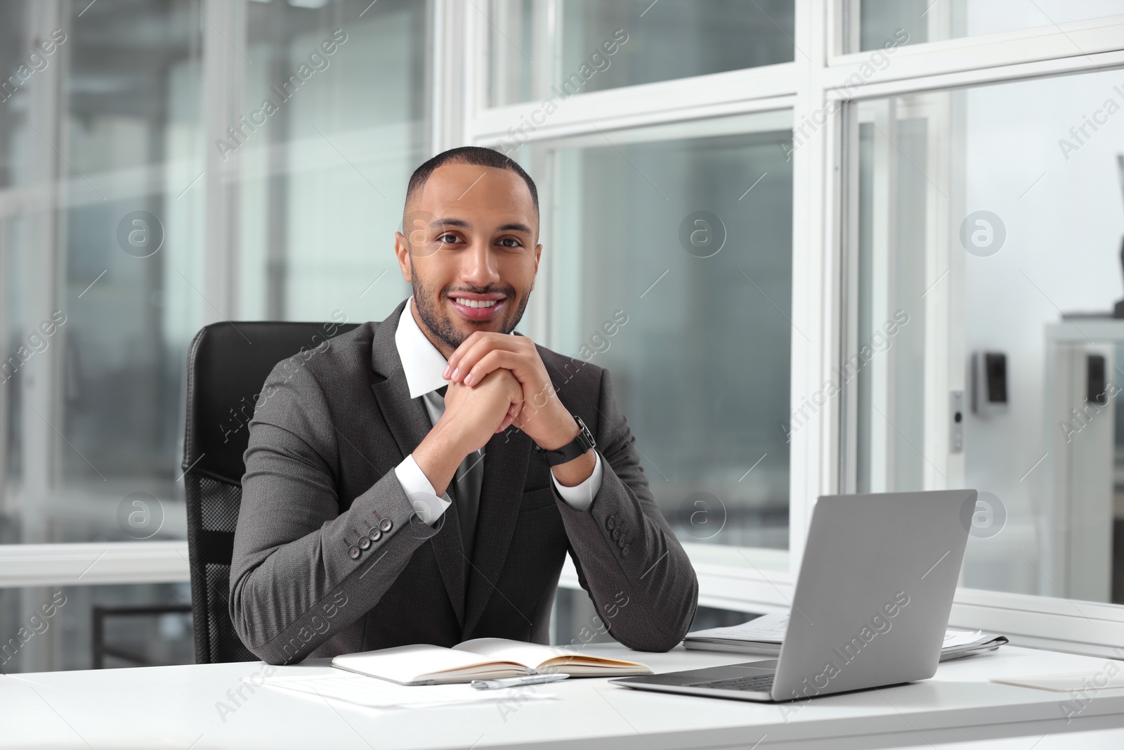 Photo of Happy man working at table in office. Lawyer, businessman, accountant or manager