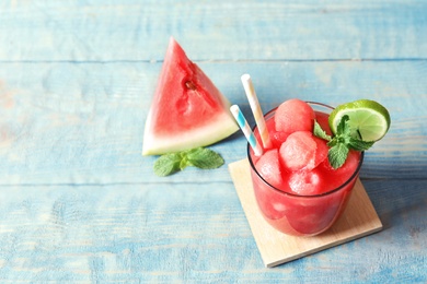 Photo of Summer watermelon drink in glass, sliced fruit and space for text on table