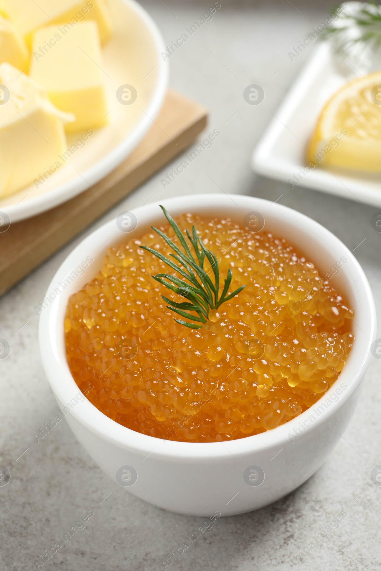 Photo of Fresh pike caviar and dill in bowl on light grey table, closeup