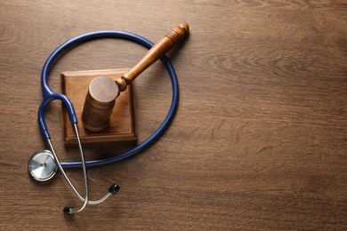 Law concept. Gavel and stethoscope on wooden table, top view. Space for text