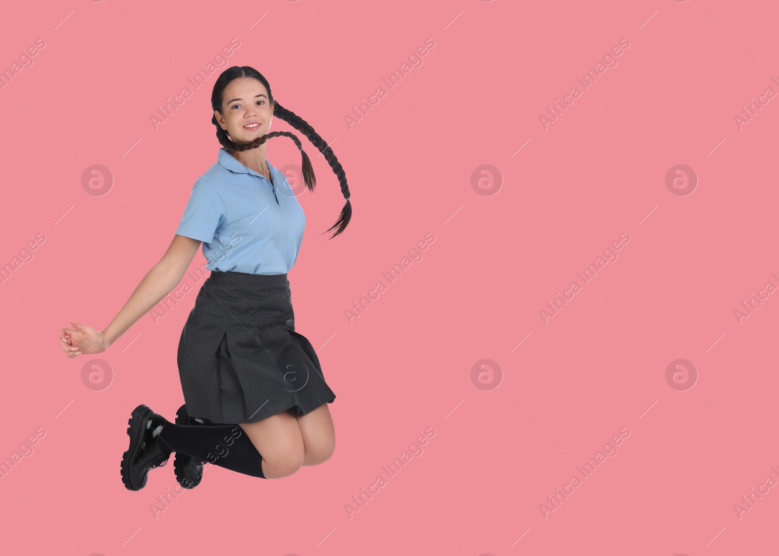 Image of Happy girl in school uniform jumping on pink background, space for text