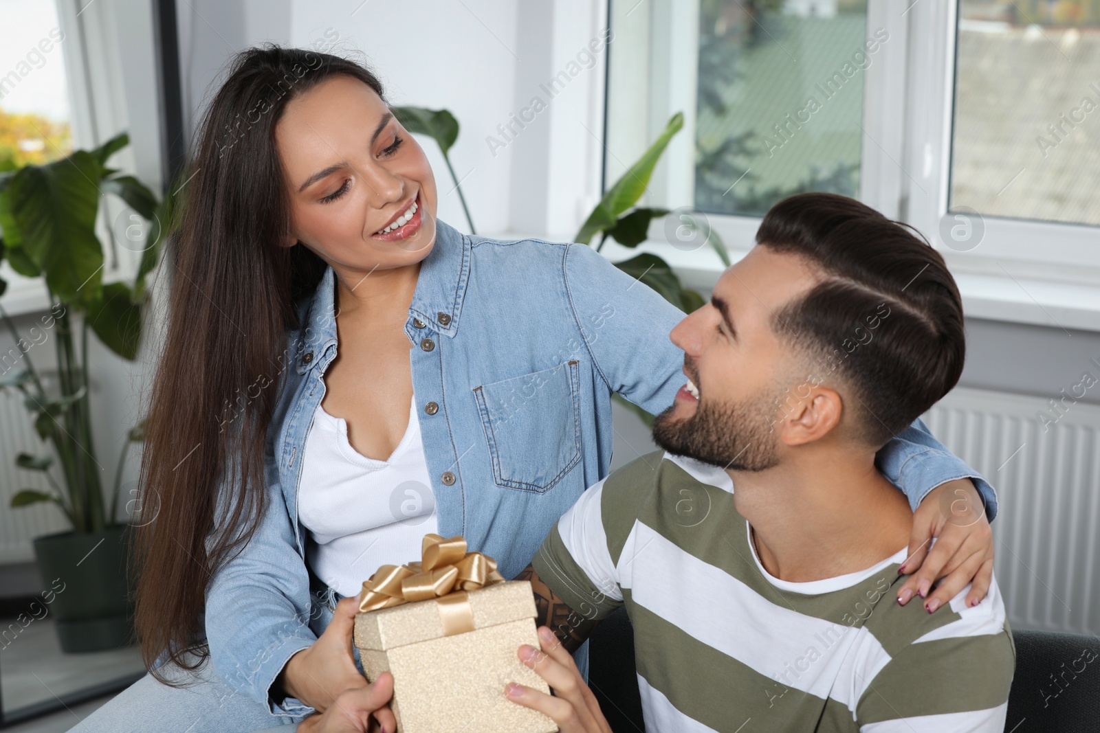 Photo of Woman presenting gift to her boyfriend at home