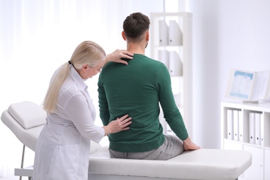 Photo of Chiropractor examining patient with back pain in clinic