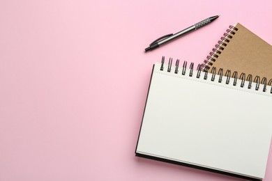 Photo of Notebooks and pen on pink background, top view. Space for text