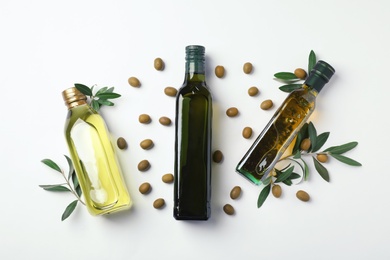 Flat lay composition with bottles of olive oil on light background