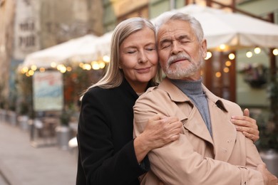 Portrait of affectionate senior couple on city street, space for text