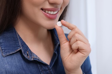 Photo of Woman taking pill on blurred background, closeup