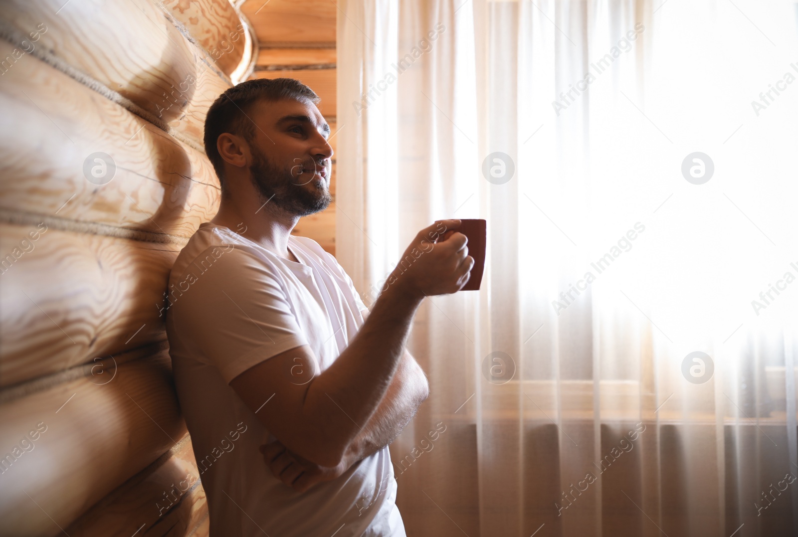 Photo of Man with drink near window indoors. Lazy morning