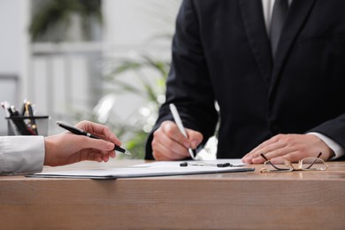 Woman reading document at table in office, closeup. Signing contract