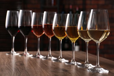 Different tasty wines in glasses on wooden table