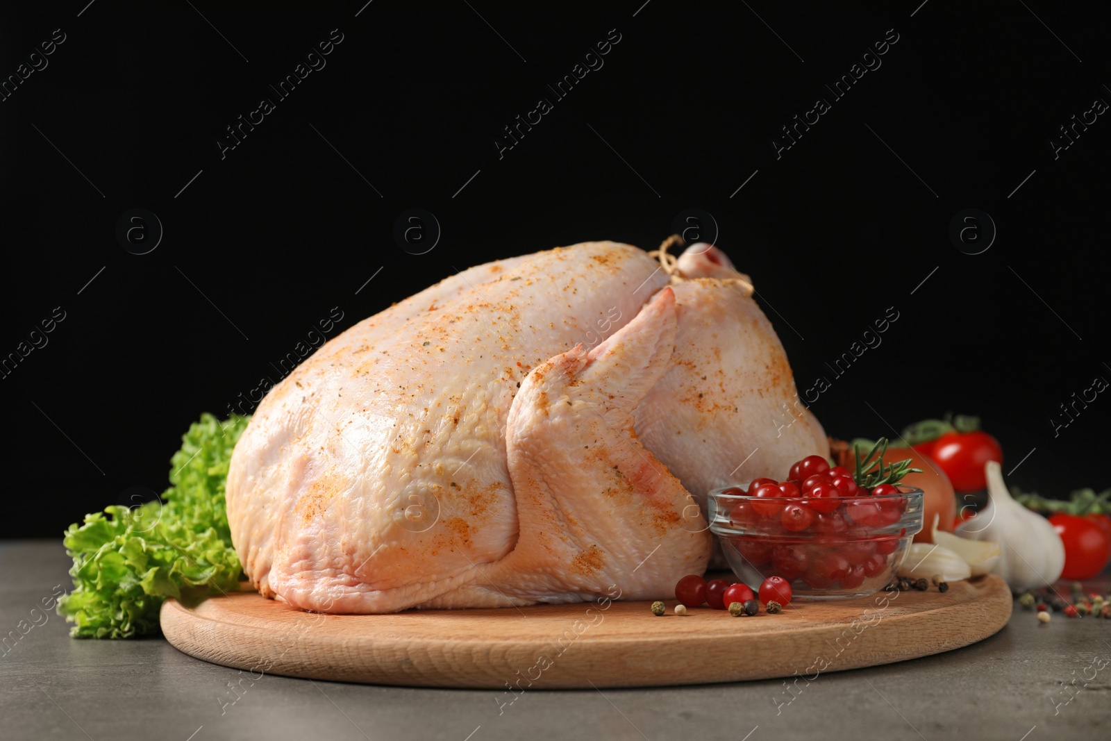 Photo of Wooden board with raw spiced turkey and ingredients on table