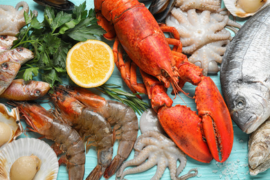 Photo of Fresh fish and different seafood on blue wooden table, flat lay